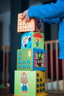 Un enfant jouant à l'intérieur, empilant des blocs de jouets en bois colorés avec des illustrations joyeuses